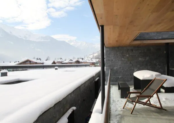 Verschneite Terrasse des Smaragdresorts mit Blick auf die Berge